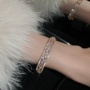 Close-up of triple-row gold bracelet with pink and white cubic zirconia on a fur sleeve