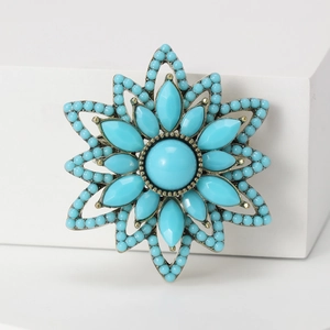Macro detail of vintage gold floral brooch with turquoise stones on white background