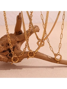 Close-up of assorted 18k gold plated stainless steel chains hanging on natural wood branch