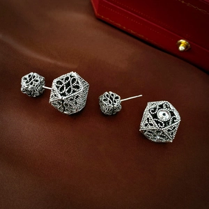 Orecchini vintage in argento geometrici con texture traforata su sfondo di seta scura
