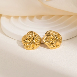 Macro shot of gold textured geometric stud earrings on a cream aesthetic background