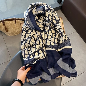 Close-up of the silk-like scarf with classic letter D pattern in navy and beige