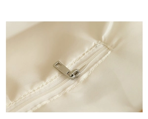 Close-up of the smooth metal zipper and neat stitching on a beige fabric handbag