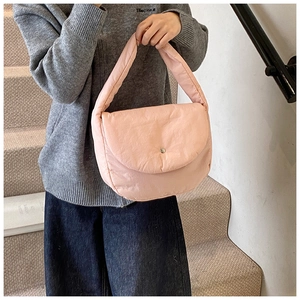 Detail of light pink quilted puffer bag with magnetic clasp on a female model