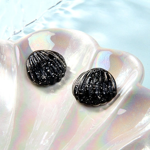 Glittering black shell resin accessories displayed in a pearlescent white tray