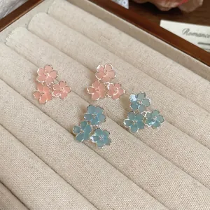 Boucles d'oreilles fleurs en résine rose et bleue dans un écrin en velours beige