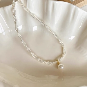 Detailed macro view of vintage pearl necklace with a large pearl pendant in a shell tray