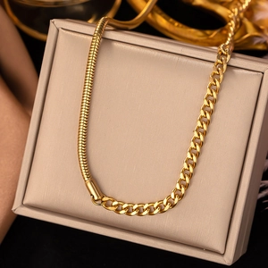 Detail of gold spliced necklace featuring snake and curb chain on a beige stand