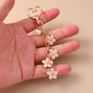 Detailed shot of pink cherry blossom charms and pearl on a golden metal keychain