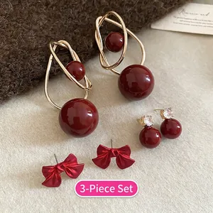 Detailed view of three pairs of vintage gold and red earrings with pearls and bows