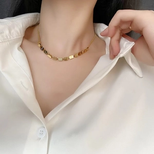 Close-up of gold LOVE square block pendant necklace on a gold snake chain for women