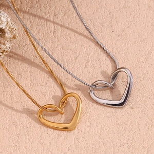 Detail of 18K gold and silver plated heart pendants on delicate snake chains over texture