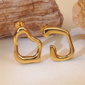 Artistic close-up of chunky gold irregular geometric earrings on natural rock texture