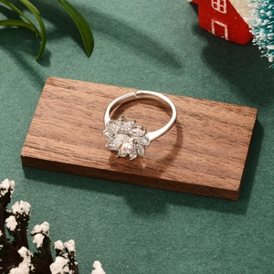 Detailed shot of an adjustable silver flower ring with crystal stones on a wood block