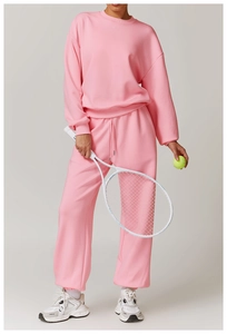 Détail de l'ensemble de sport rose avec sweat à col rond, pantalon de jogging et raquette
