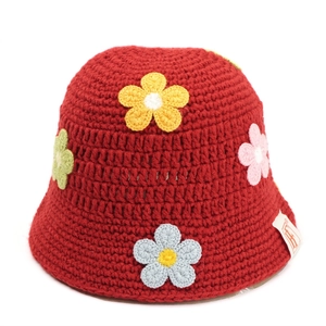 Close-up of handmade red crochet bucket hat with colorful floral patterns and woven texture