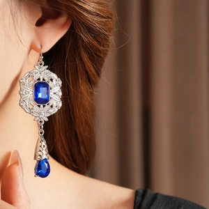 Detailed macro view of vintage drop earrings with blue crystal stones and silver hollow design