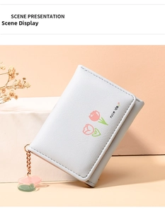 Detail of light blue tri-fold wallet featuring pink tulip print and heart charm