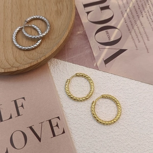 Chic textured stainless steel hoop earrings in gold and silver finish on a wooden tray