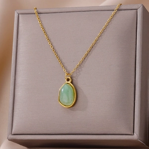Macro shot of gold-plated geometric necklace with a translucent green gemstone pendant