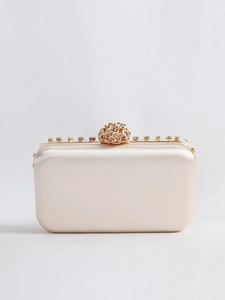 Detailansicht des funkelnden Strass-Blumenverschlusses an der champagnerfarbenen Satin-Clutch