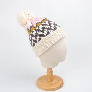 Close-up of geometric knit beanie with pompom showing ribbed texture and wave pattern