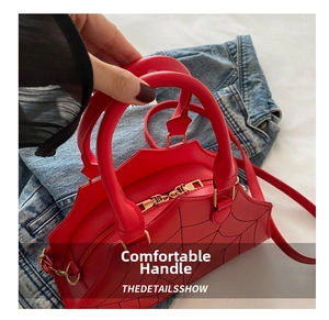 Detail of red spider web stitching on handbag with gold dual zipper and dual handles