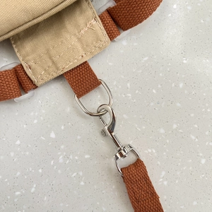Detalle de la mochila arnés para perro en lona caqui con correas naranjas y hebilla metálica