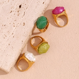 Close-up of four 18K gold plated rings with irregular red, green and white resin stones