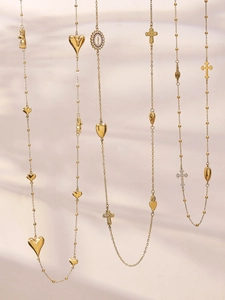 Detail van gelaagde gouden kettingen met hart-, kruis- en zirkoon-medaillonhangers