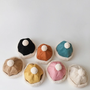 Flat lay of colorful winter suede beanies for kids with plush trim and pom-pom detail