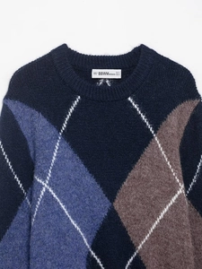 Detail of the crew neck collar with brand label and blue argyle pattern knit sweater
