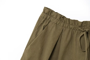 Detailed view of elastic waistband with drawstring on dark olive woven shorts