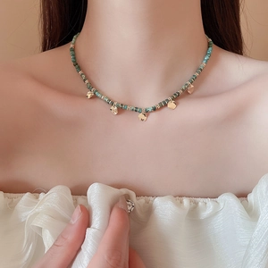 Détail du collier de perles turquoise avec accents dorés et pendentif sur le cou