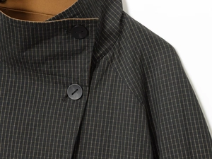 Detail of checkered fabric collar and shoulder with a brown inner layer and black button