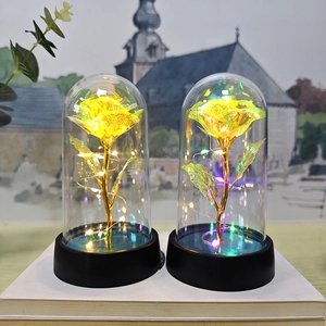 Detailed view of luminous gold foil rose with colorful LED lights in glass dome on black base