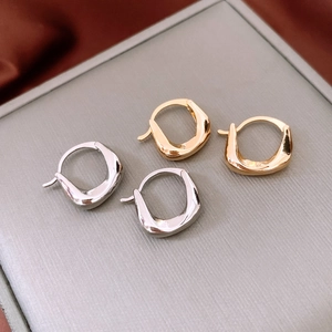 Close-up of irregular twisted hoop earrings in polished gold and silver finishes
