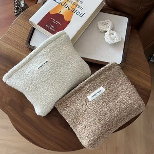 Close-up of beige and brown tweed cosmetic bags with woven texture and zipper closure