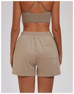Detail of light khaki sports shorts featuring elastic high waist and back patch pocket