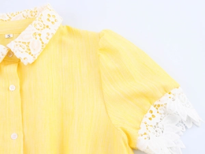 Detail of yellow dress showing cotton texture and white lace trim on collar and sleeves