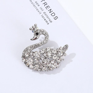 Detailed view of luxury silver swan brooch with crystals on a fashion magazine background