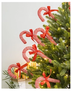 Close-up of red and white striped candy cane ornament with a silk bow on a Christmas tree