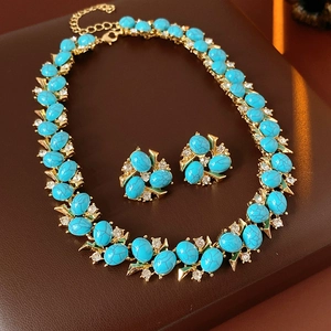 Vue macro d'une parure vintage dorée avec pierres turquoise et accents de zircon clair