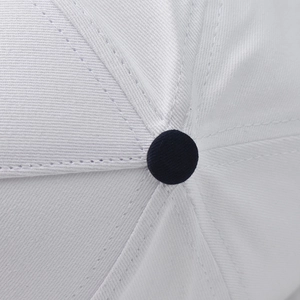 Detailed macro view of white cotton twill baseball cap top with navy blue button
