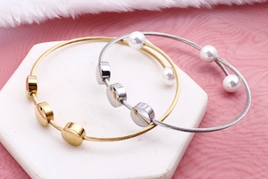 Detail view of gold and silver steel wire bangles with pearls on stone stand