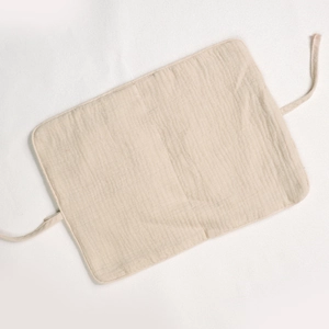 Close-up of beige cotton crib organizer fabric with tie straps and natural texture