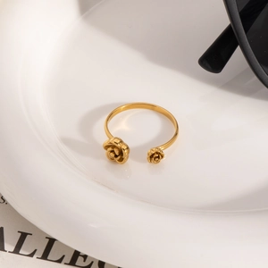 Minimalist double-headed rose open ring in gold stainless steel on a white ceramic plate