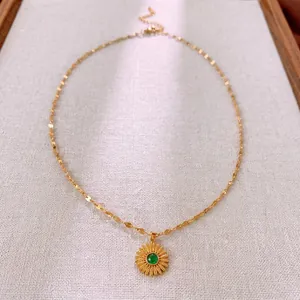 Vintage golden sunflower necklace with green emerald gemstone on a rustic jewelry box