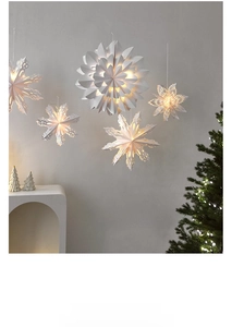Hanging white paper snowflake pendants with warm LED lights in a cozy interior setting