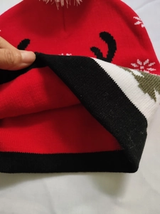 Close-up of the red knitted Christmas hat showing thick white lining and deer pattern